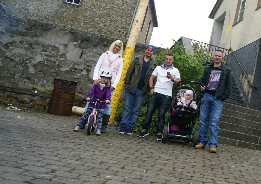 Maibaumbegutachtung vor der Kirche Jessica Fischer (l.) mit den Töchtern Amelie und Hanna und ihrem Mann Ronny (r.) vor dem Baum, den vor Milan Schmidt (3.v.l.) und Steve Martin mit ihren Freunden vorher aufgestellt hatten. : Foto: Mittelhessenblog