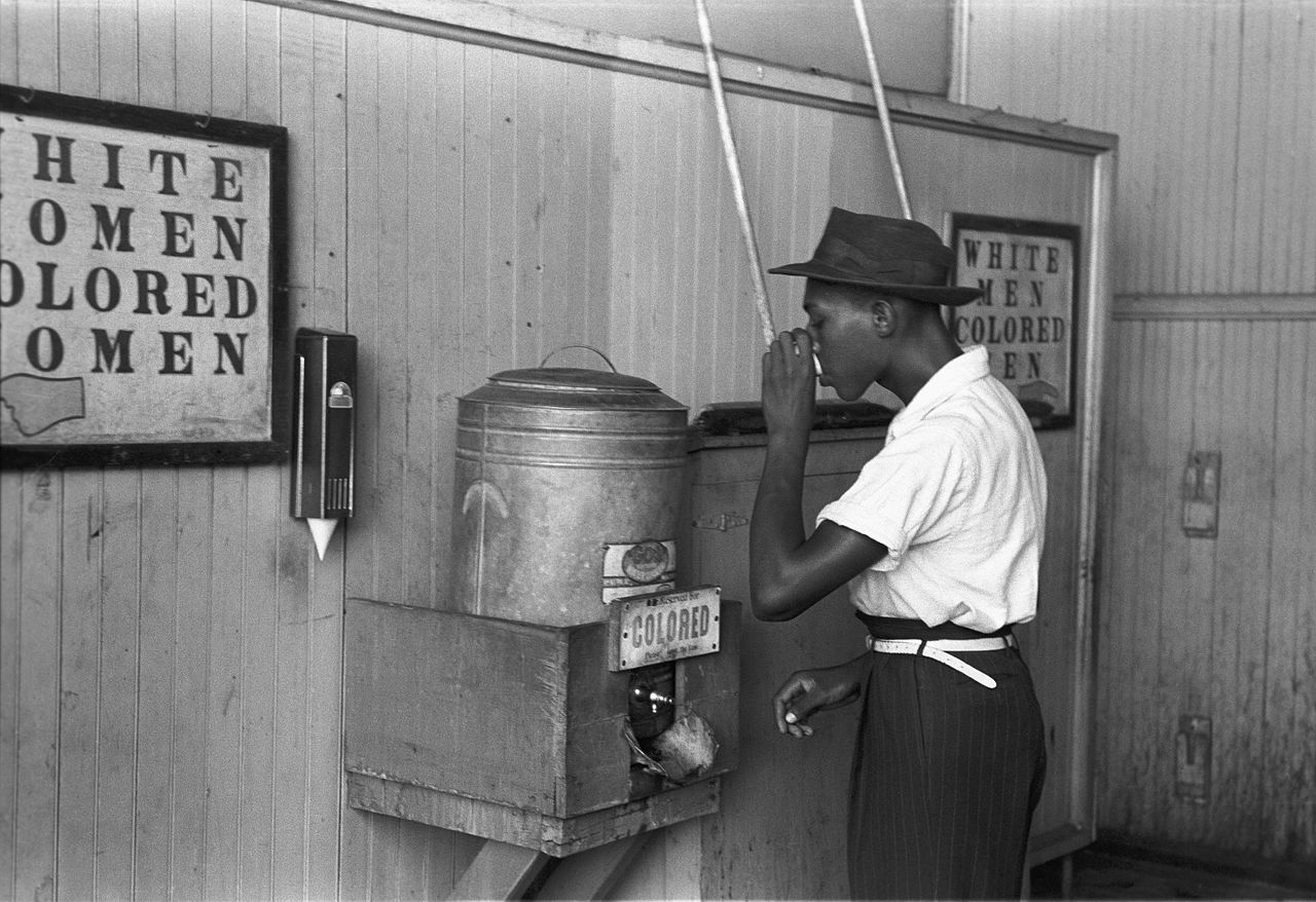 USA 1939: Ein Afroamerkaner trinkt aus einem Wasserbehälter, der ausschließlich farbigen vorbehalten ist. Elle-Chefredakteurin Katell Pouliquen muss am 10. Februar 2017 erleben,dass sie beim Einkaufen in ihrer bretonischen Heimatstadt St. Brieuc mit ihren beiden Söhnen, die dunkelhäutig sind, ebenfalls wegen deren Hautfarbe beschimpft wird......Bild: Wikipedia.fr Russell Lee, 1939